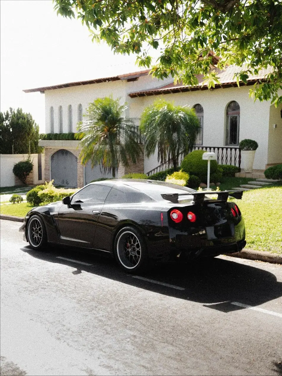Nissan GT-R R35 preto visto de trás em uma rua arborizada