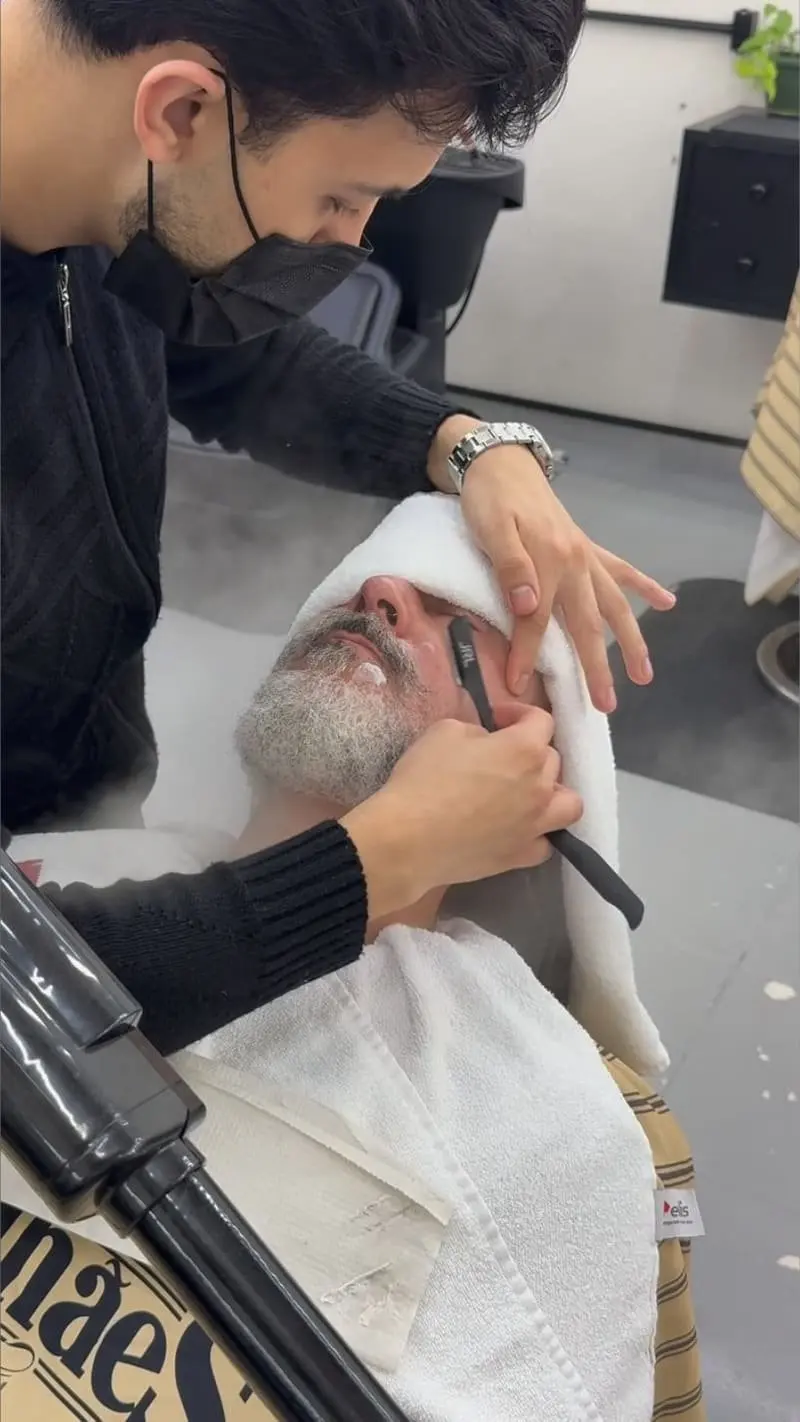 Barbeiro finalizando barba com navalha