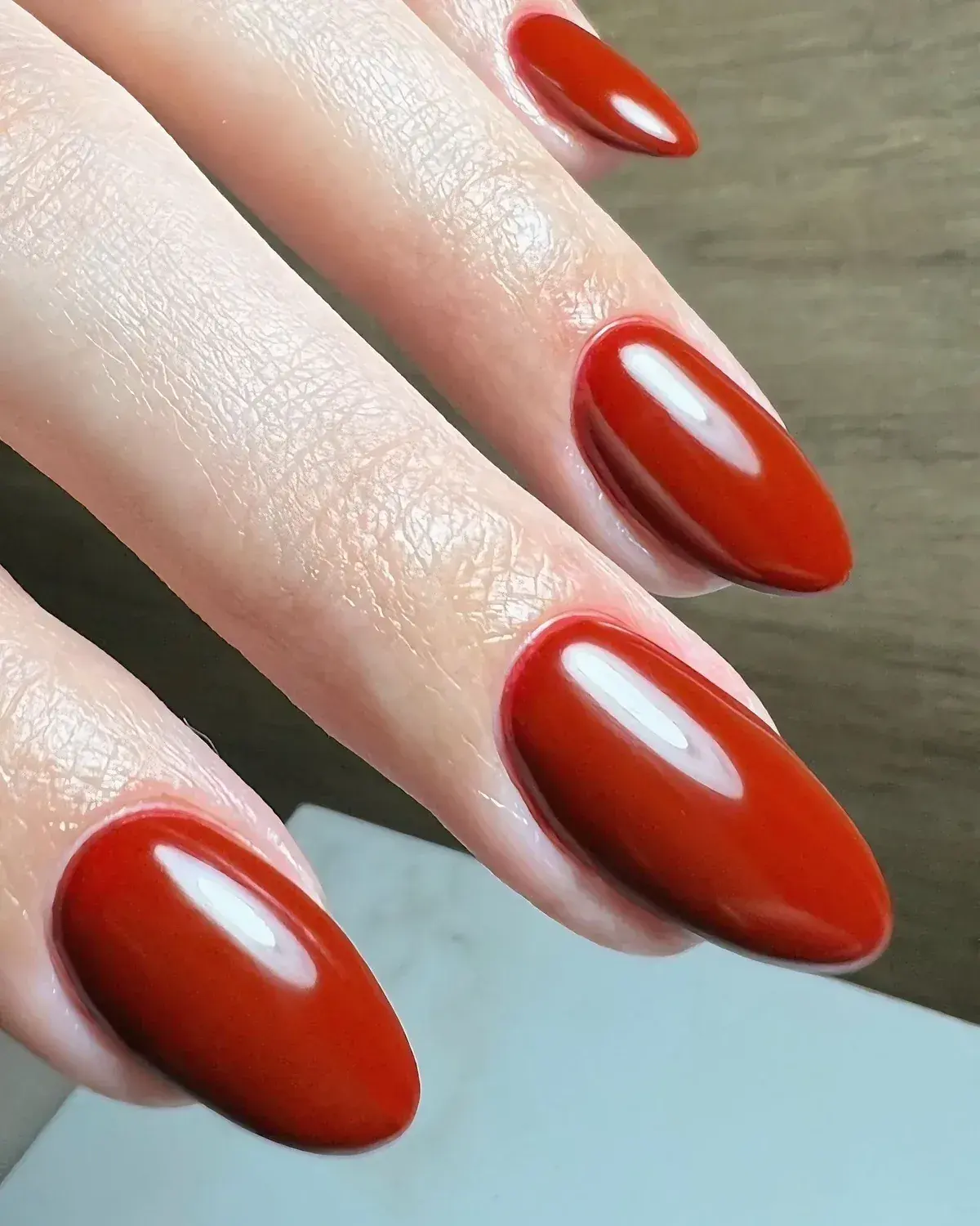 Unhas em formato amêndoa esmaltadas em vermelho terracota